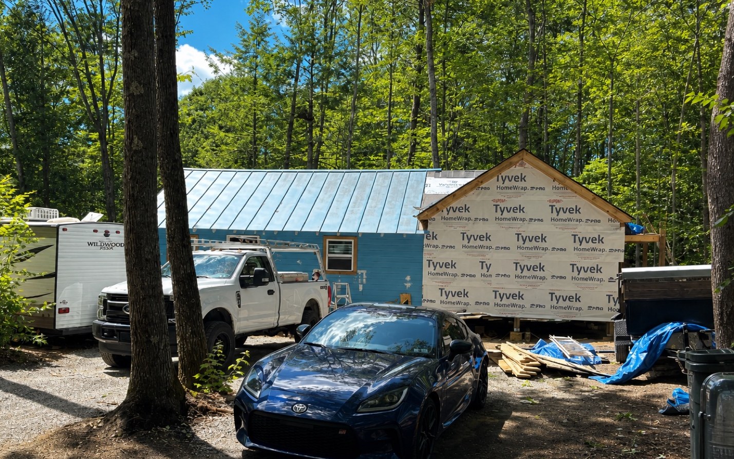 Canterbury cabin with Tyvek-wrapped addition and trucks on the job site